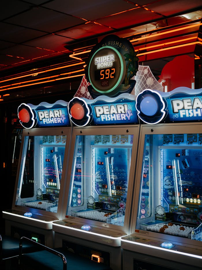 A close-up of colorful pearl fishery arcade machines illuminated by neon lights in an indoor gaming arcade.