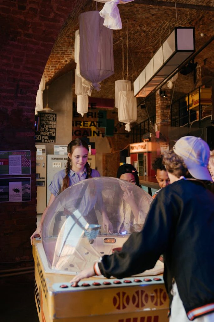 Group of teenagers playing vintage arcade games in an indoor setting.